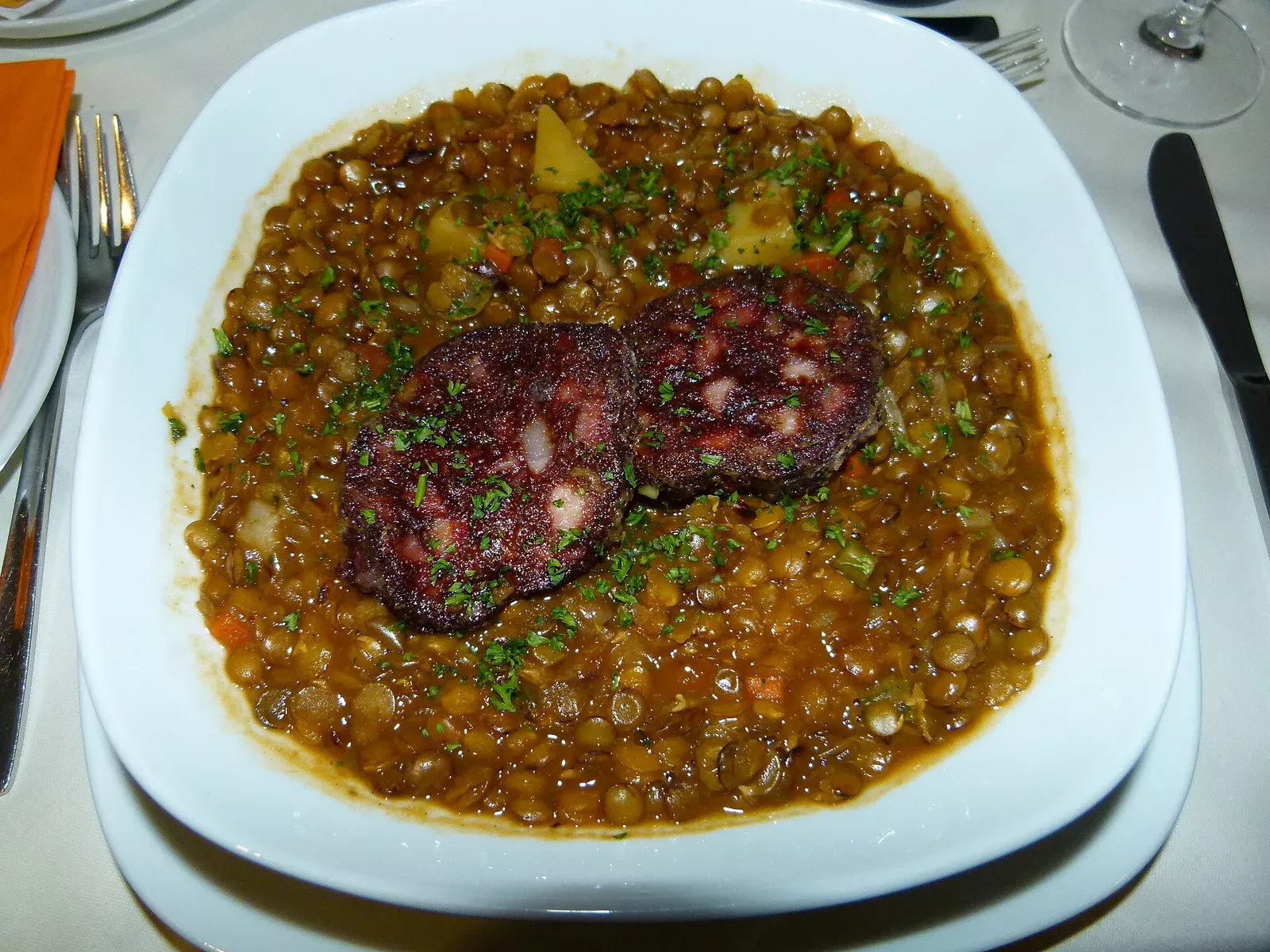Deftige Linsensuppe mit knusprigem Speck und Wurzelgemüse in einem handgetöpferten Steintopf
